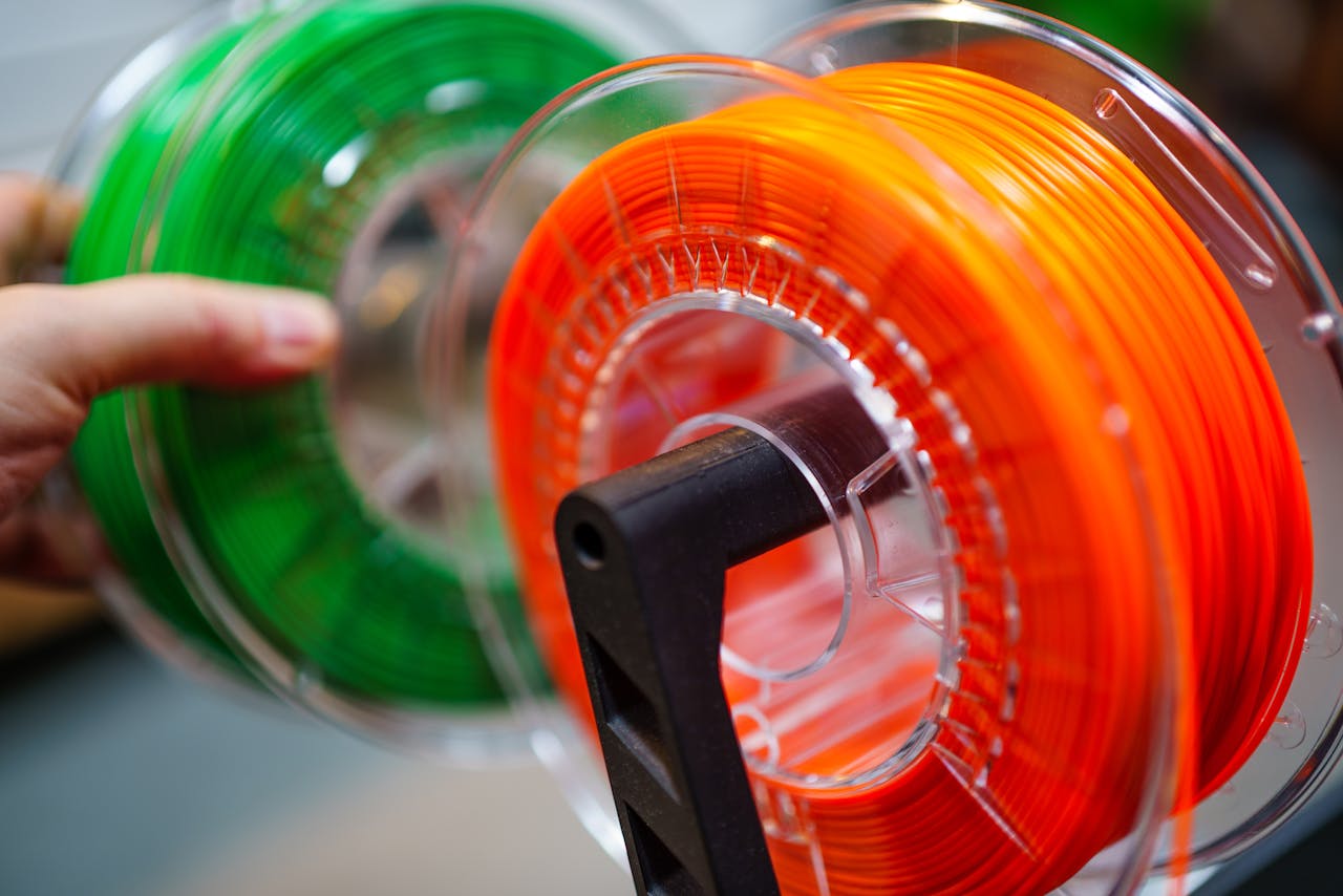 awards-img Vibrant orange and green 3D printer filament spools for innovative manufacturing uses.